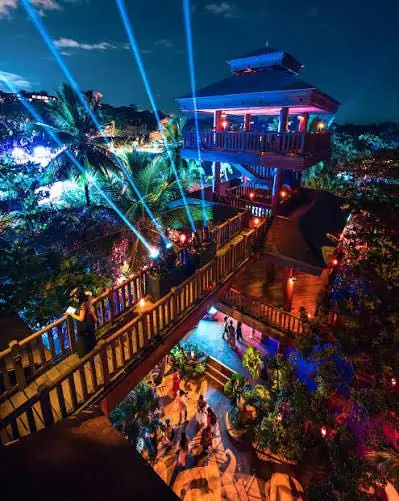 A pavilion and bridge lit up with beams of light at night
